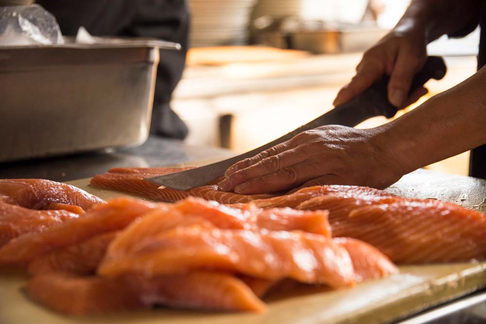 A chef cutting through salmon fillets