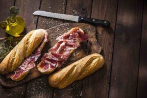baguette with slices of prosciutto on brown table. Sandwich in San Francisco
