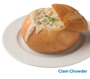 Clam chowder in a sourdough bread bowl on a plate with the caption Clam Chowder