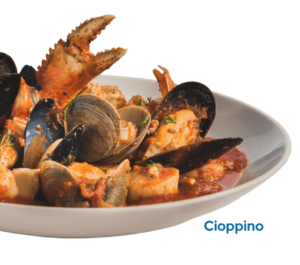 Crab, fresh fish, shrimp, scallops, clams, and mussels stewed in a seafood tomato broth in a bowl with the caption Cioppino