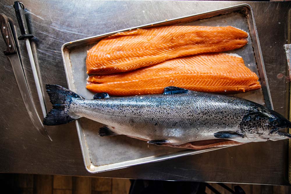 A whole fish and salmon fillets on a platter