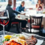 Steak and lobster on a plate with red wine on table