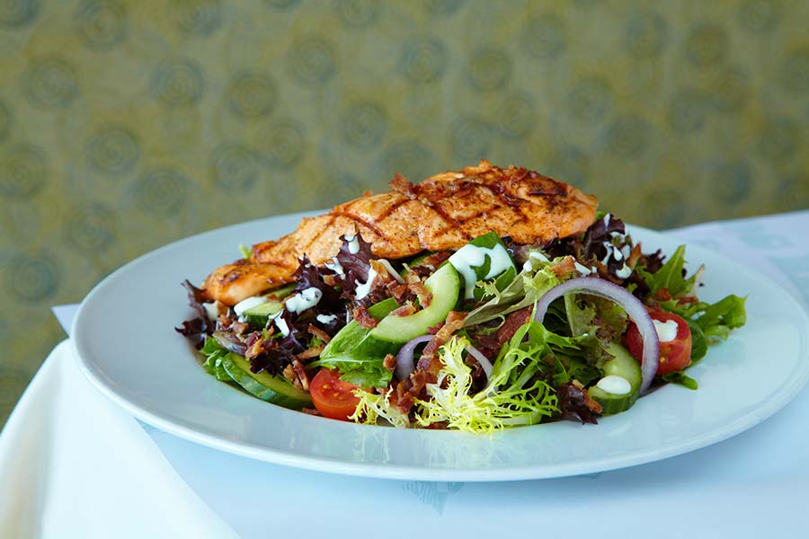 A salad with grilled meat on top
