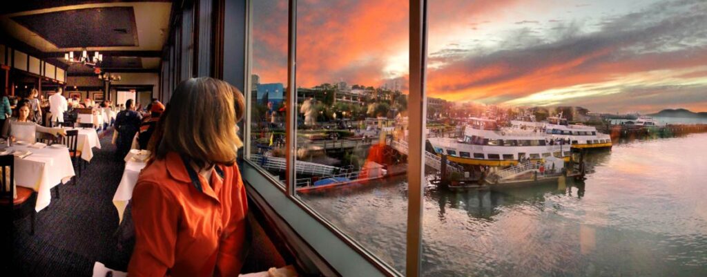 A woman enjoying a sunset from Fog Harbor windows