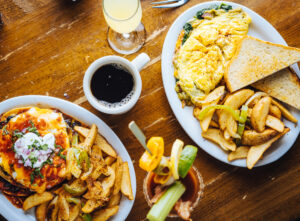 Plate of black bean and eggy chilaquiles with a side of spiced potato wedges, served with coffee and a mimosa